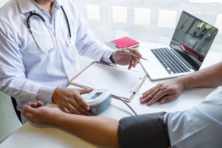 Médico aferindo a pressão arterial de um paciente durante a consulta